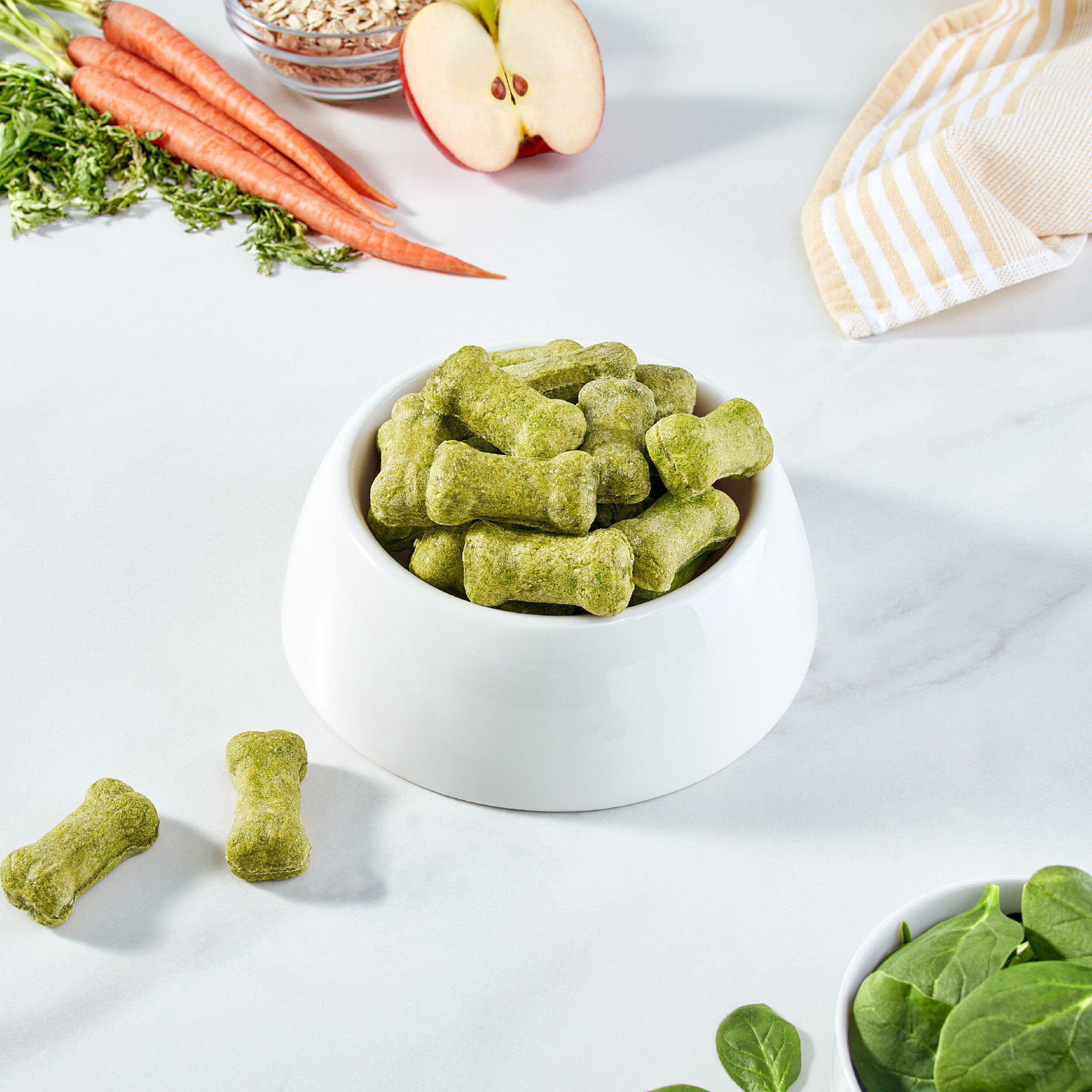 Un plato blanco para perro lleno de galletas verdes en forma de hueso.