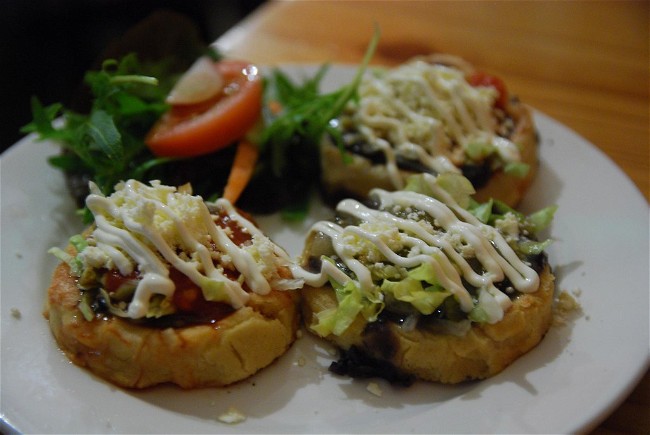 Image of Sopes (thick tortillas topped with beans, meat, lettuce, cheese, and salsa)