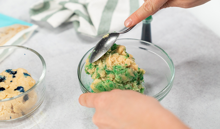 Image of  Add 3 drops of green food coloring to one bowl, and blue food coloring to the other bowl. 