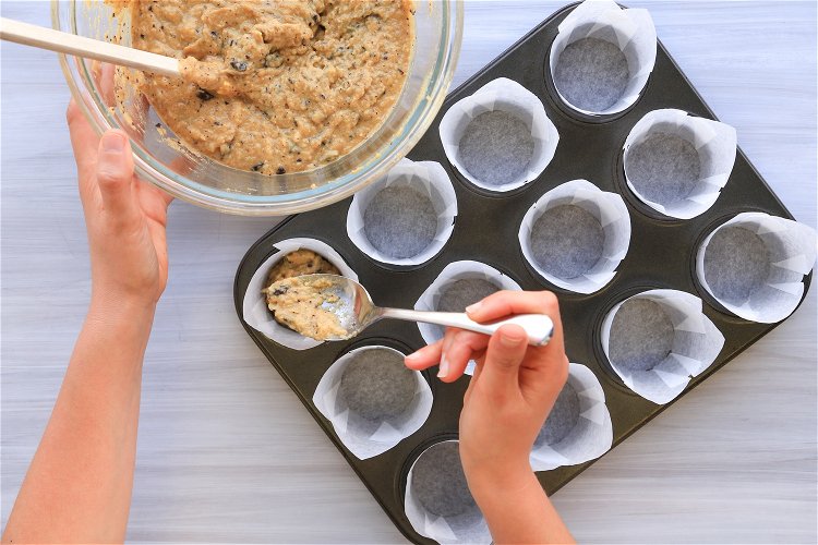 Image of Using a spoon, portion mix into the 12 muffin wrappers....