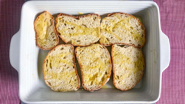 Image of Grease a 9x13-inch pan. Butter bread sliced and lay in the pan, buttered side up. Layer with cheese and meat. If cooking right away, preheat oven to 350