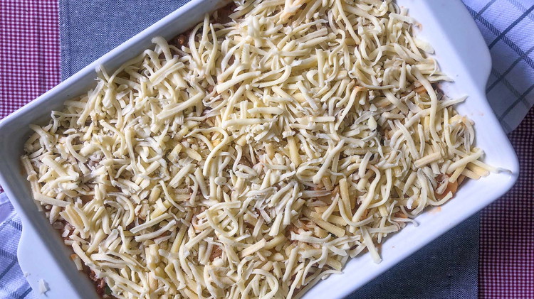 Image of Spoon noodles into a greased 9x13 pan casserole and top with layer of cheese.