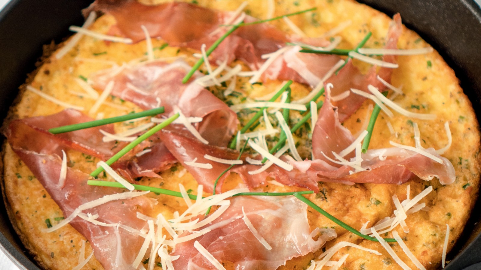 Dutch baby in cast iron skillet with prosciutto and parmesan.