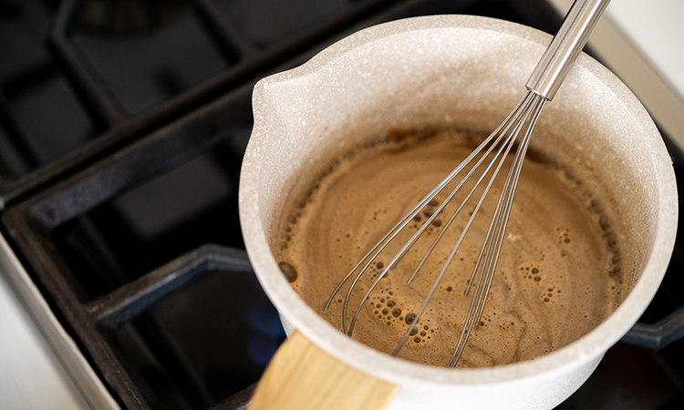 Image of In a medium saucepan, add the water, butter, cinnamon, Lakanto Classic Sweetener, and vanilla.  Whisk and the ingredients until it comes to a boil.  Remove from heat and allow the mixture to rest for 3 minutes.