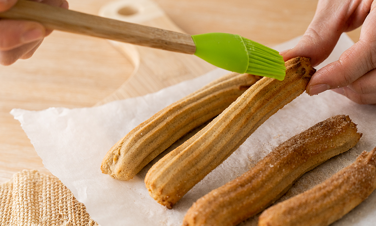 Image of Using a basting brush, brush the churros with melted butter and sprinkle over or roll in cinnamon/sweetener mixture. 