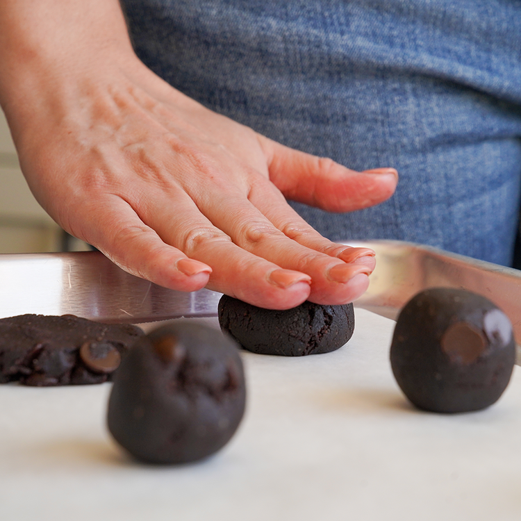 Image of Slightly flatten with hands or a utensil into desired thickness (cookies bake into similar shape they are placed into the oven). 