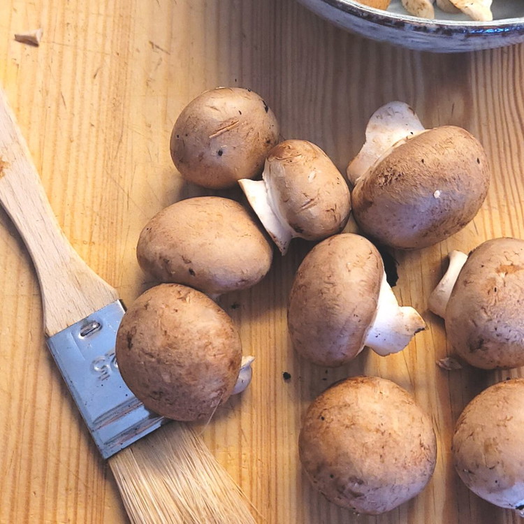 Image of Die Champignons mit einem Pinsel putzen und wenn nötig vierteln