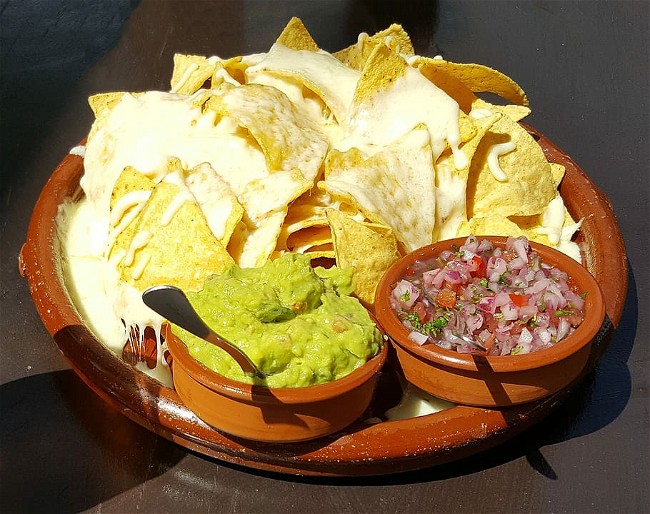 Image of Chilaquiles verdes (tortilla chips simmered in green salsa and topped with cheese and cream)