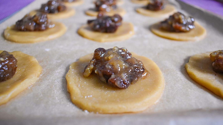 Image of Place cut-out circles onto a lined cookie sheet. Scoop a heaping teaspoon of raisin filling in the center of each cookie.