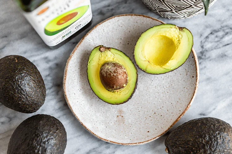 Image of While the eggs are cooking, cut avocado in half.