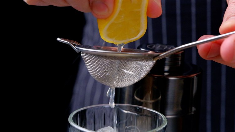 Image of Dann werden der Gin, Zitronensaft und Zuckersirup in das Glas...