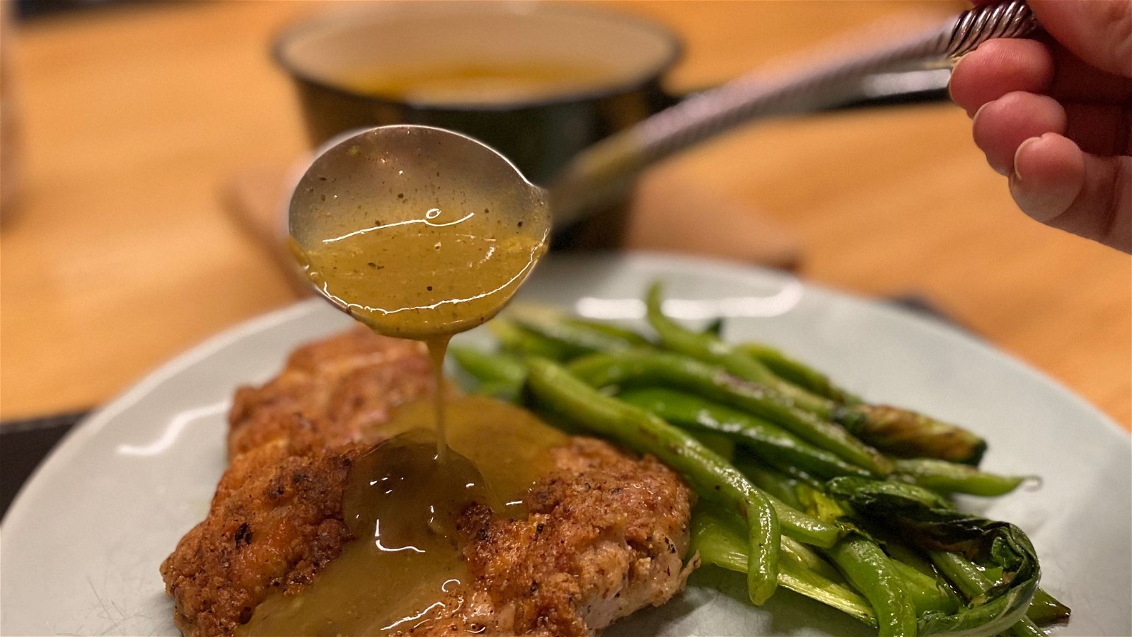 Image of garlic pepper sauce being spooned onto garlic pepper chicken schnitty