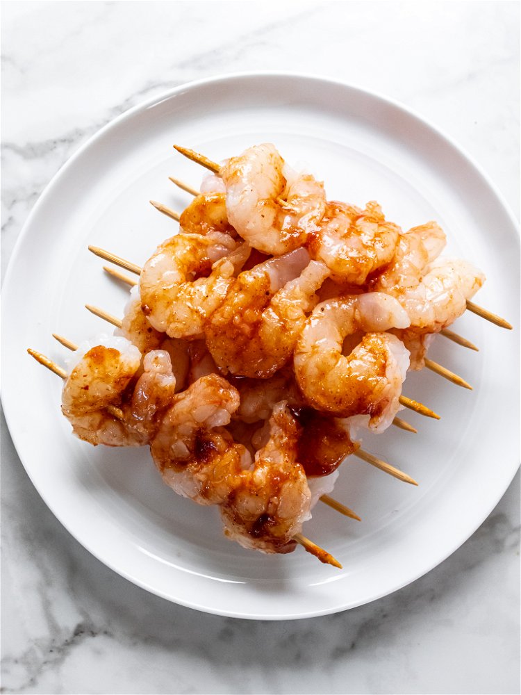 Image of Grease grill grates with cooking oil and place shrimp skewers...