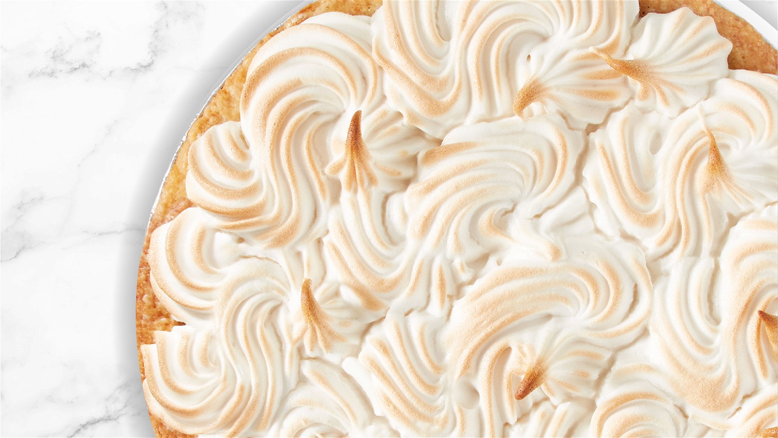 Top down view of a Lemon Meringue Pie on a marble countertop.