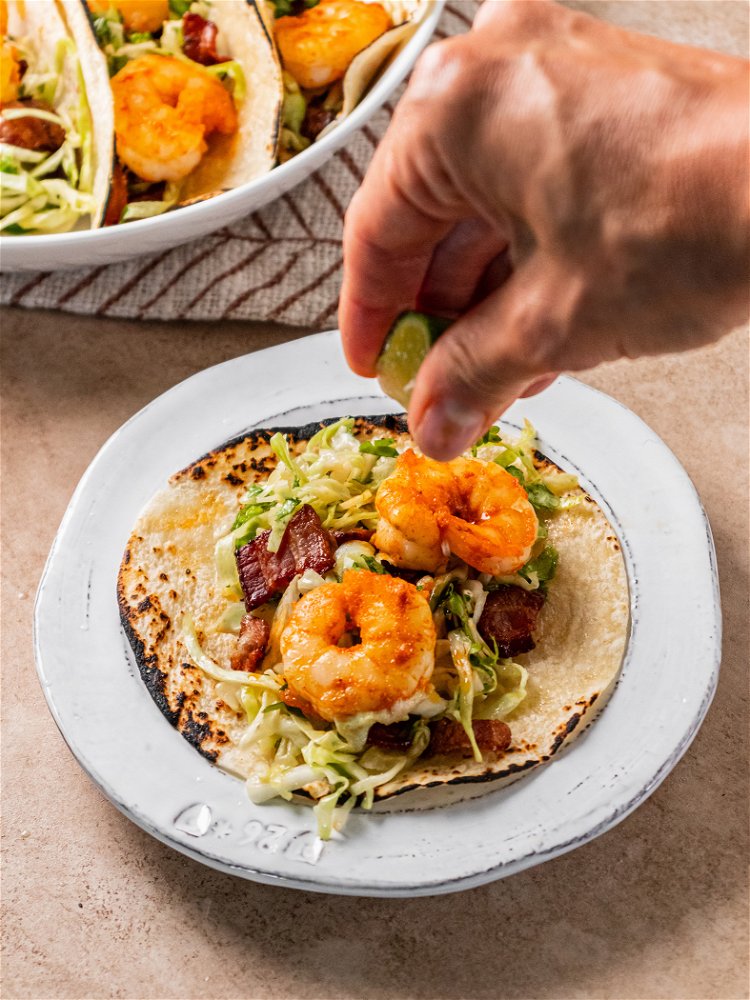 Image of Serve slaw over tortillas topped with warm shrimp. 