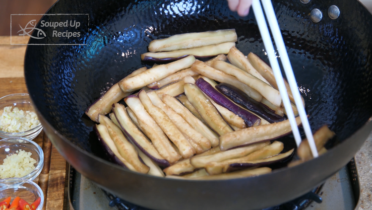 Image of Add the minced garlic, ginger, diced Thai bird chilies, fermented black beans, and the Sichuan dou ban jiang to the same wok. Stir over low heat until fragrant.