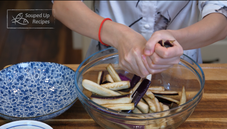 Image of Squeeze the eggplant to eliminate the excess moisture, then rinse under running water to wash off the salt. Drain the eggplant and squeeze again.