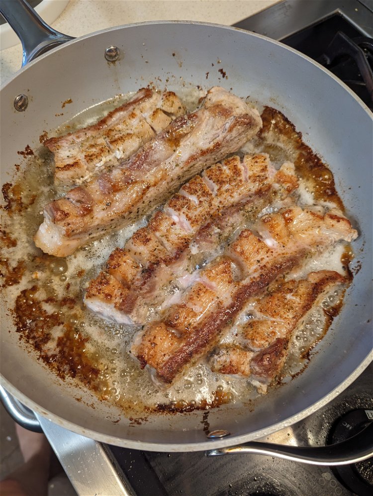 Image of On medium heat, fry the pork belly slices in oil...