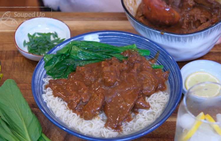 Image of Spoon the satay beef, including the sauce, on top of the noodles and sprinkle diced scallion as garnish.