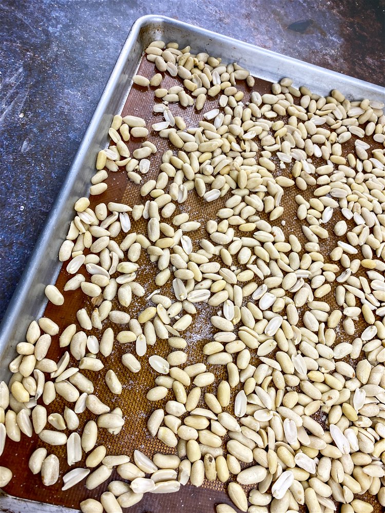 Image of Pour peanuts onto the prepared baking sheet and spread into...