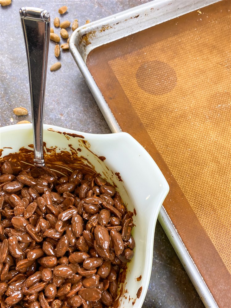 Image of Add the roasted peanuts one scoop at a time to...