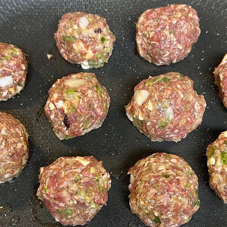 Image of Heat a skillet over medium heat with a little olive oil. Once the skillet is heated, add your meatballs and cook them. Rotate your meatballs every five minutes to evenly sear the outside of all sides of the meatball.