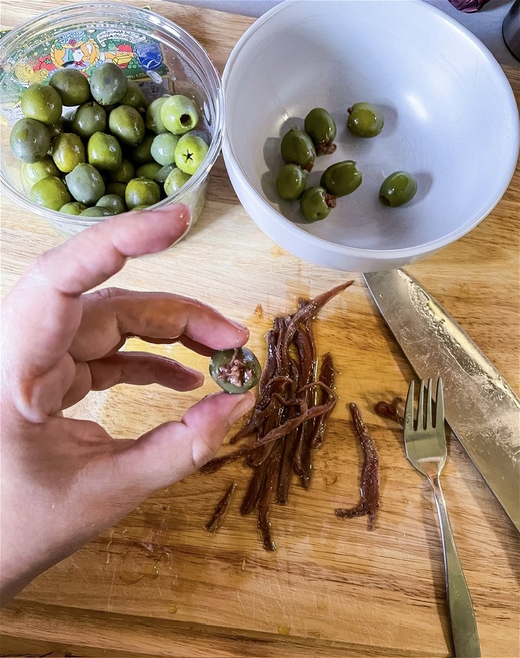 Image of Using a toothpick, stuff your olives with the anchovies to...