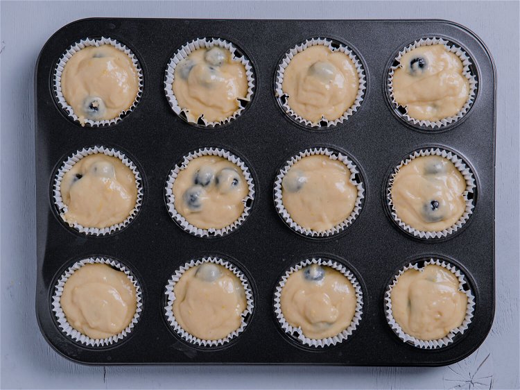 Image of Divide the batter between the prepared muffin cups.