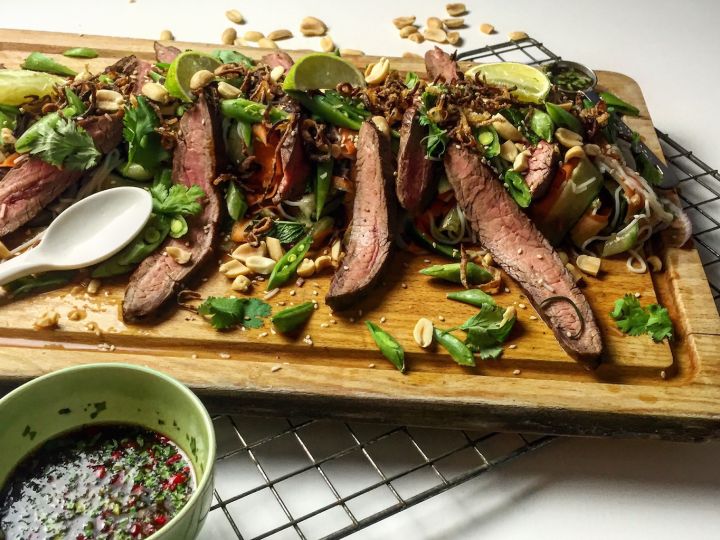 Image of Slice the steak in long strips and blend together with the salad. Plate the salad and pour over the remaining dressing. Garnish with the crispy onions, sugar snaps, mint leaves, crushed peanuts and coriander