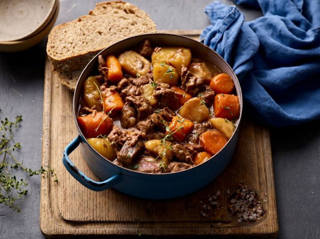 A steak casserole in blue dish and bread
