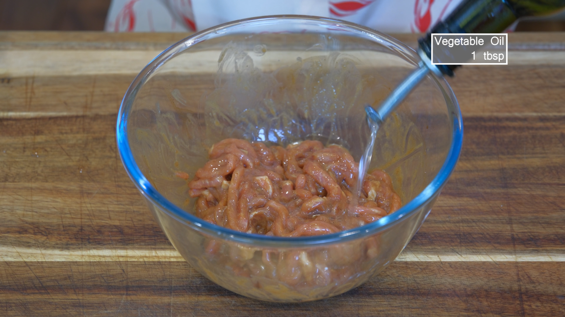 Image of Add a big drizzle of oil to the meat and give it a rough mix. The oil prevents the pork strips from tangling, making it easier to stir fry later. Set it aside.