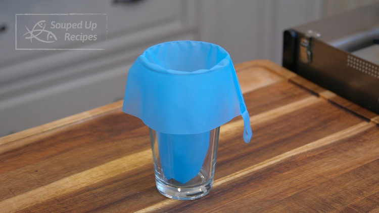 Image of Put a piping tip into a piping bag. Twist the tip, then place the bag into a cup. Set it aside.
