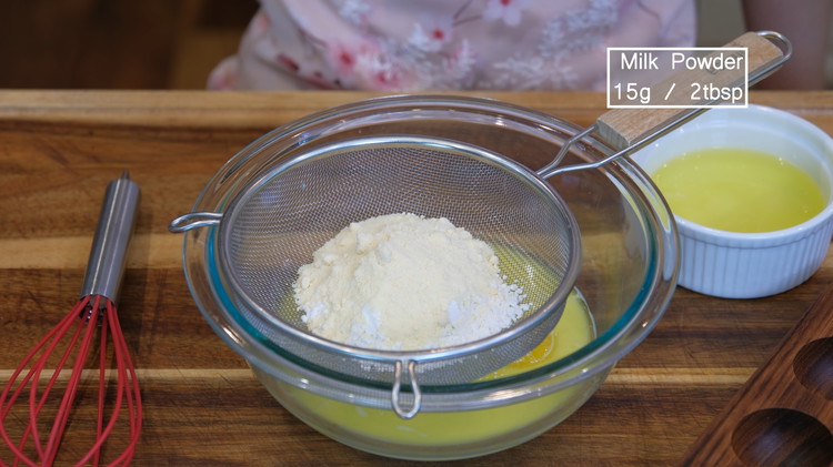 Image of Sieve in the cake flour and milk powder, then stir until no lumps.