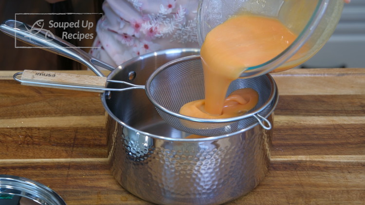 Image of Mix well and pour the mixture through a sieve into a saucepan. Heat the mixture over low heat and stir constantly for 5-6 minutes or until the consistency becomes solid and separates from the bottom of the pan.