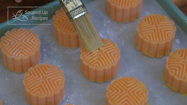 Image of Brush the egg yolk onto the surface of the mooncake, including the top pattern and the sides.