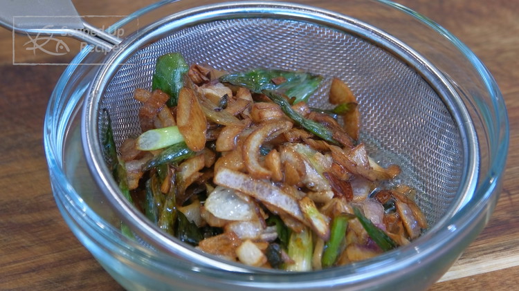 Image of Separate the aromatics and the oil by pouring them through a sieve. Reserve the crispy goodness on the side.