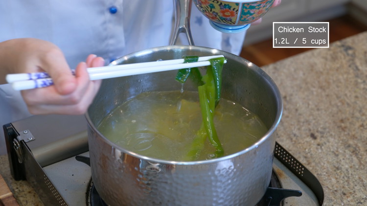 Image of Remove the scallions and ginger slices from the pot. Then put the chicken broth back onto the stove and heat it over medium heat.