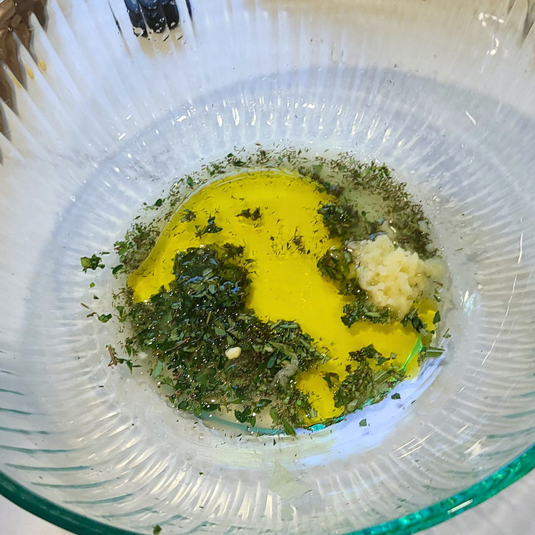 Image of In a large mixing bowl, combine the olive oil, minced garlic, lemon zest, chopped herbs and a generous sprinkle of salt and pepper.