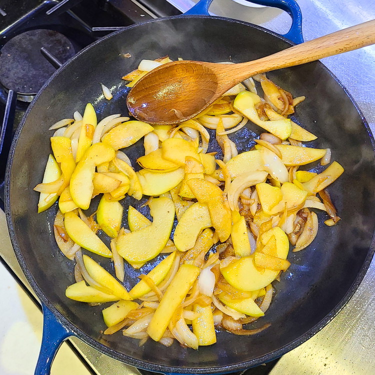 Image of In a large skillet, heat the butter over medium heat. Add the sliced apples, onions and minced garlic and cook until they become translucent and start to brown just a little, about 6-8 minutes.