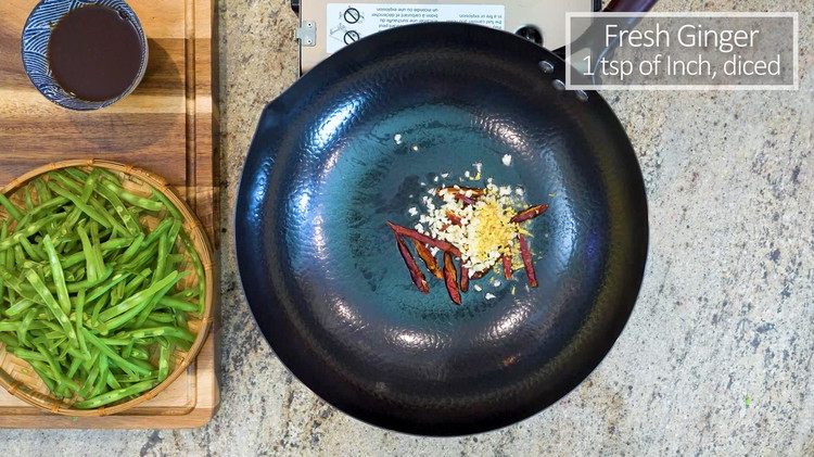 Image of Add oil to the wok. Doesn’t need to wait for the oil to get hot. Just directly add in the red dried chilies, diced garlic, and ginger. Stir over medium heat for a minute or until fragrant.