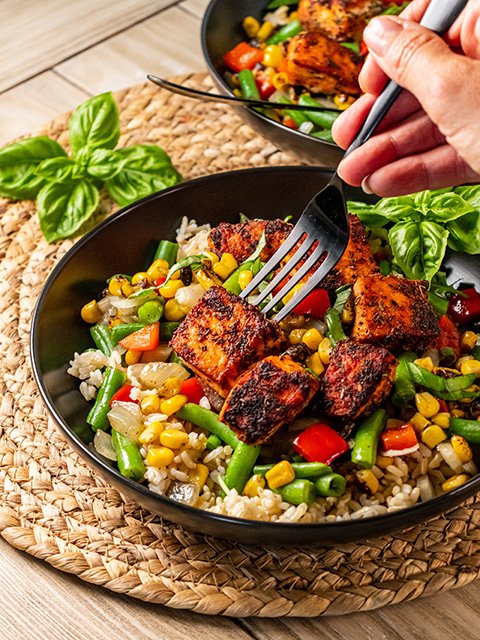Image of Divide vegetables and blackened salmon over brown rice in two...