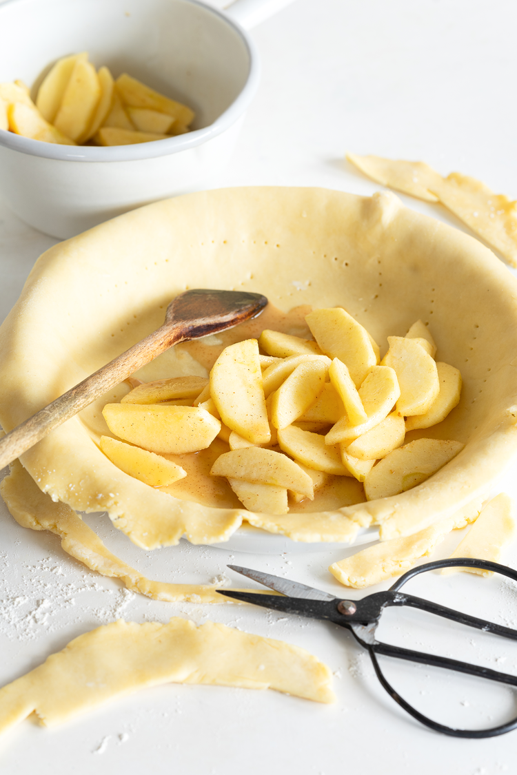 Image of Teig halbieren und eine Pie-Form (Durchmesser 26cm) mit Butter einstreichen. Auf etwas Mehl die eine Hälfte des Teigs sehr dünn, rund und etwas größer als die Form ausrollen und dann in die Form legen. Den Rand mit einer Schere etwa...