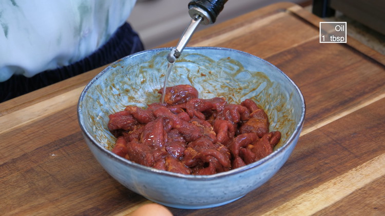Image of Add a big drizzle of oil and mix to coat the beef. This helps to separate the meat slices, making them easier to stir fry later. Set the beef aside for 15 minutes.