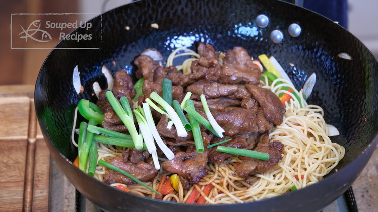 Image of Pour in the sauce. Introduce the beef back to the wok and add the scallion stalks. Keep mixing until everything is well mingled.