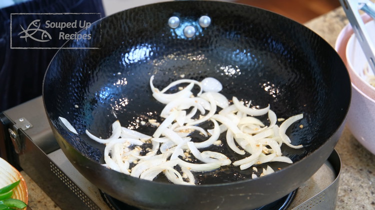 Image of Turn the heat back to medium. Add the onion and garlic. Stir for a couple of minutes or until the onion is soft.