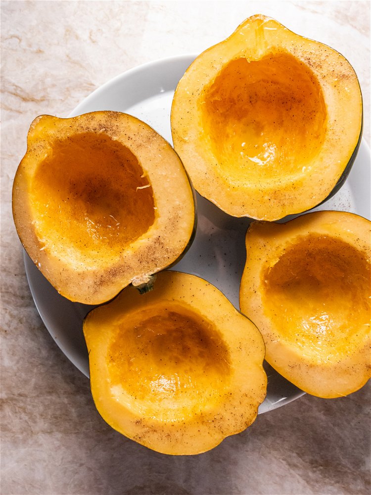 Image of Slice acorn squash in half lengthwise and scoop out seeds...