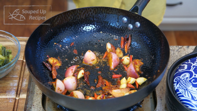Image of Heat the wok over medium heat and add oil. Toss in ginger, shallot, garlic, Thai bird eye chilies, dried red chilies, and sichuan dou ban jiang. Stir for a couple of minutes.