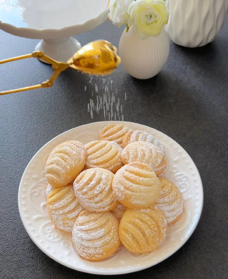 Image of Allow the cookies to cool on the baking sheet. Dust them with powdered sugar after cooling.