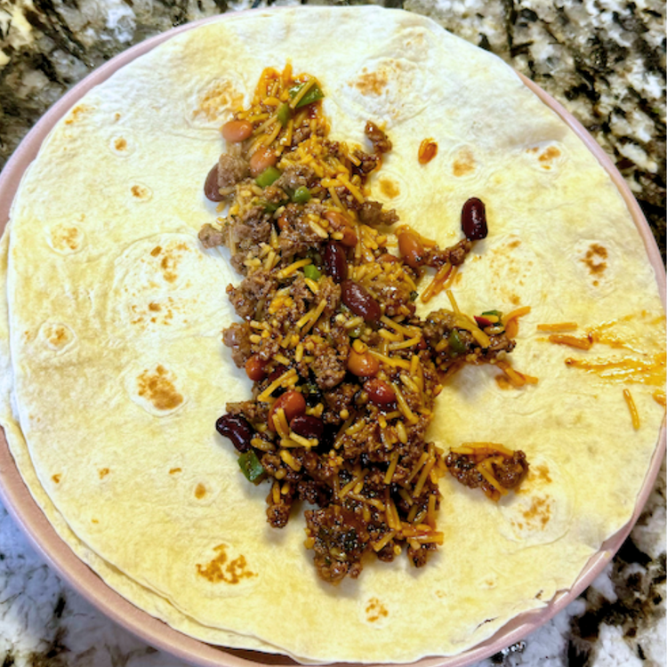 Image of Once the ground elk is cooked, add in the beans and rice. Warm through then assemble your burritos. Add the meat mixture to the middle of a tortilla.
