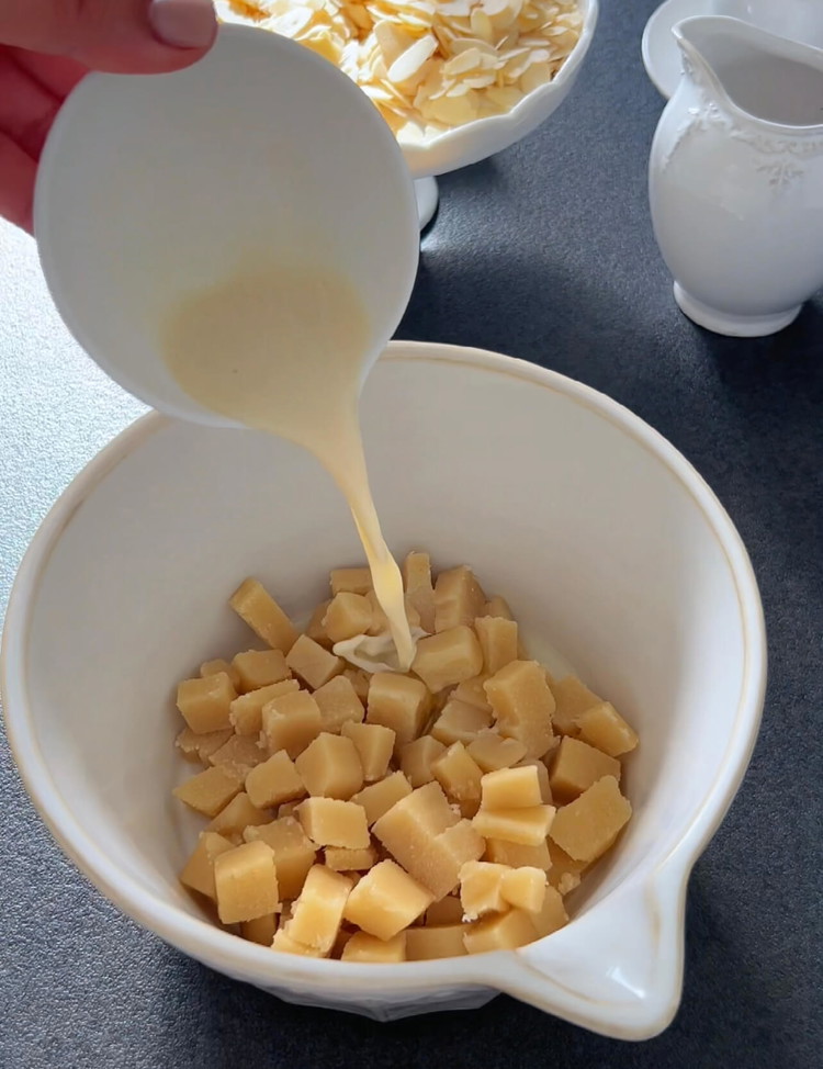 Image of Em outra tigela, combine o marzipã picado, o leite de amêndoa, a essência de amêndoa amarga e as claras de ovo. Sove a mistura com uma batedeira até formar uma massa homogênea.